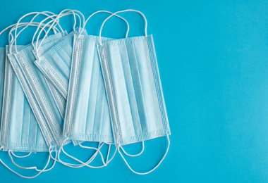 Mavi arka planda tıbbi koruyucu maskeler. Koronavirüsü önlemek için ağzı ve burnu kapamak için 3 katlı tıbbi maske. Coronavirus karantinası. Covid-19 'u korumak için antivirüs tıbbi maskesi.