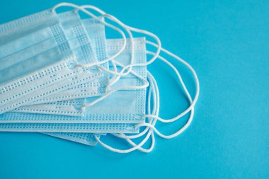 Mavi arka planda tıbbi koruyucu maskeler. Koronavirüsü önlemek için ağzı ve burnu kapamak için 3 katlı tıbbi maske. Coronavirus karantinası. Covid-19 'u korumak için antivirüs tıbbi maskesi.
