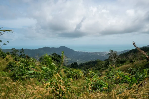 Un chemin de terre entre la jungle et les montagnes. Chemin de terre rural dans la forêt tropicale en Thaïlande avec vue sur la ville et la mer . — Photo