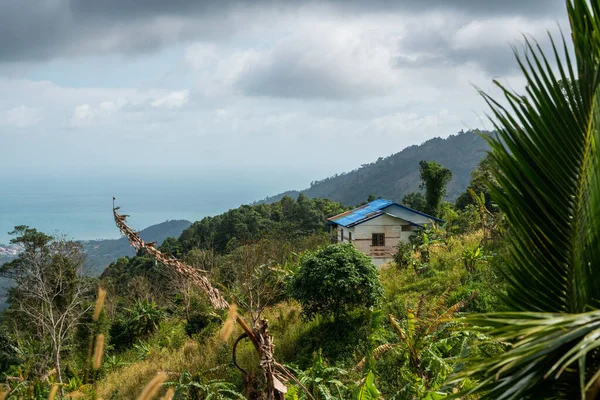 Piccola casa di campagna sulle colline della foresta tropicale con un cielo nuvoloso. Montagne e nuvole bianche su un cielo blu . — Foto Stock