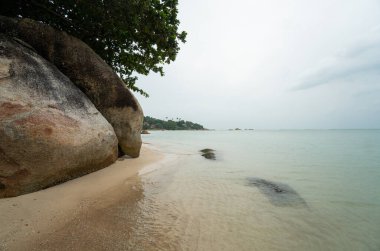 Tayland 'ın güneyindeki tropikal adada bulutlu bir günde kayalık bir sahil..