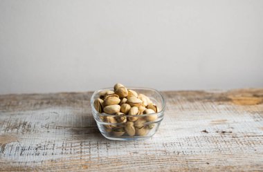 Eski ahşap bir masada küçük bir tabakta şam fıstığı. Pistachio sağlıklı bir vejetaryen protein yiyeceğidir. Doğal çerezler.