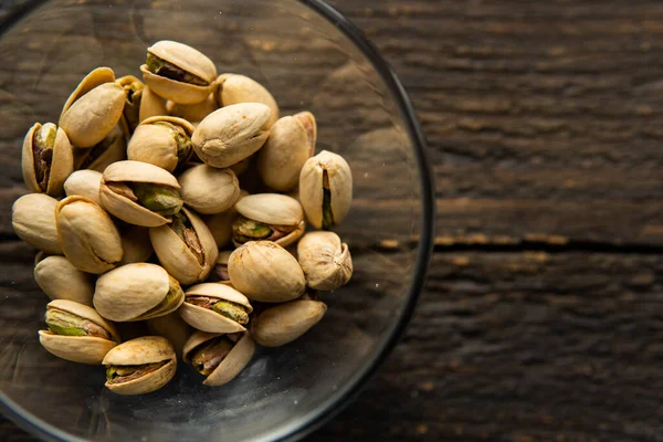 Pistazien in einem kleinen Teller auf einem Holztisch. Pistazie ist eine gesunde vegetarische Proteinnahrung. Natürliche Nüsse Snacks. — Stockfoto