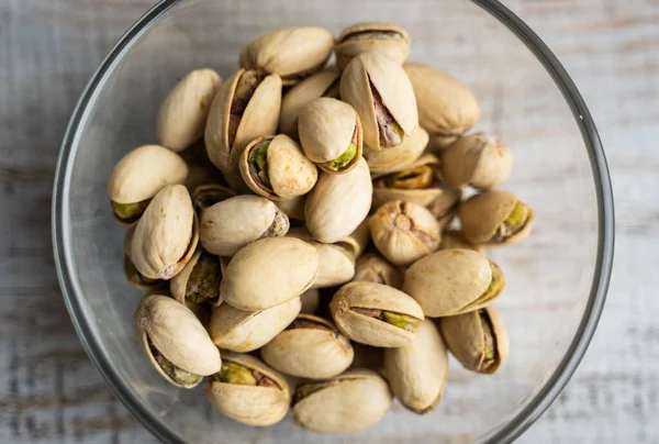 Pistachios in a small plate on a vintage wooden table. Pistachio is a healthy vegetarian protein nutritious food. Natural nuts snacks. Royalty Free Stock Images