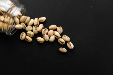 Fıstık kavanozdan siyah masaya saçılmış. Ceviz sağlıklı, vejetaryen, besleyici bir yemektir..