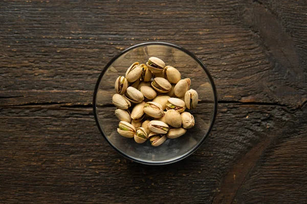 Pistazien in einem kleinen Teller auf einem Holztisch. Pistazie ist eine gesunde vegetarische Proteinnahrung. Natürliche Nüsse Snacks. — Stockfoto