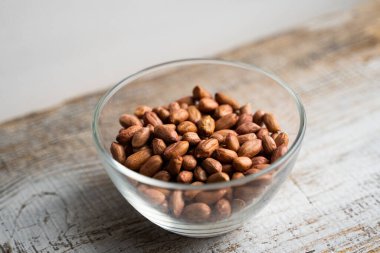 Eski ahşap bir masada küçük bir tabakta yer fıstığı. Fıstık ezmesi sağlıklı bir vejetaryen proteindir..