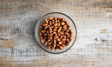 Eski ahşap bir masada küçük bir tabakta yer fıstığı. Fıstık ezmesi sağlıklı bir vejetaryen proteindir..