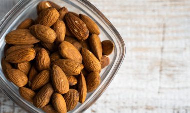Bademler eski ahşap bir masada küçük bir tabakta. Badem sağlıklı bir vejetaryen protein yiyeceğidir. Doğal çerezler.