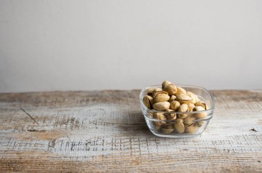Eski ahşap bir masada küçük bir tabakta şam fıstığı. Pistachio sağlıklı bir vejetaryen protein yiyeceğidir. Doğal çerezler.