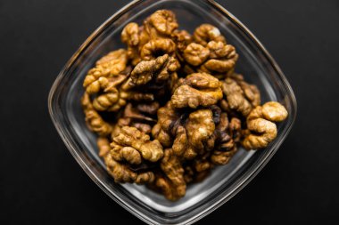 Siyah bir masada küçük bir tabakta ceviz. Ceviz sağlıklı bir vejetaryen protein besleyici gıdadır. Doğal çerezler.