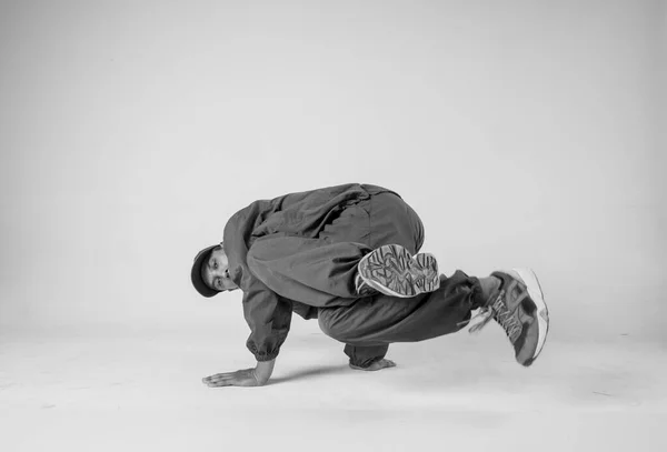 Ein männlicher Hip-Hop-Tänzer oder Bboy erstarrt in einer Pose auf weißem Hintergrund. Bboy macht stylische Stunts. — Stockfoto