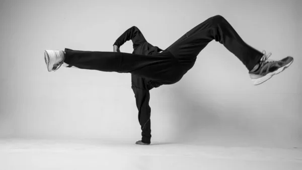 En man hip hop dansare eller bboy fryser i en pose på en vit bakgrund. Pojke gör snygga stunts. — Stockfoto