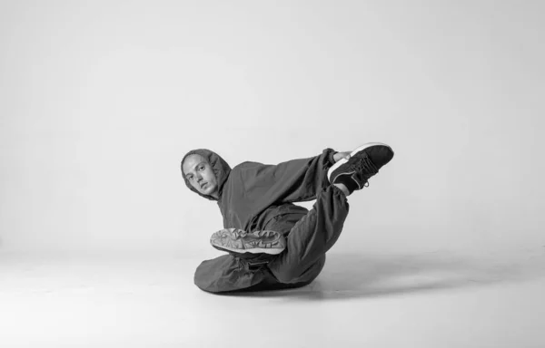 Ein männlicher Hip-Hop-Tänzer oder Bboy erstarrt in einer Pose auf weißem Hintergrund. Bboy macht stylische Stunts. — Stockfoto