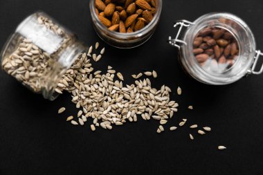 Kavanozdan siyah masaya saçılan ayçiçeği tohumları. Ayçiçeği tohumu sağlıklı bir vejetaryen proteinidir..