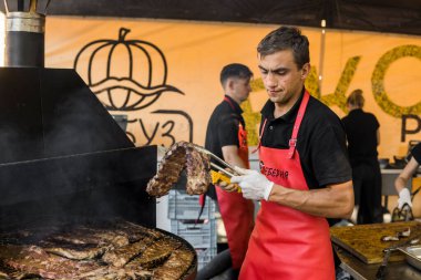 UKRAINE, LUTSK - 5 Haziran 2019: Adam yemek festivalinde domuz pirzolası pişiriyor.