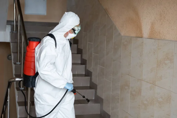 UKRAINE, KYIV - 20 mai 2020 : L'homme en costume et masque de protection blanc assainit les surfaces intérieures à l'intérieur des bâtiments tandis que l'épidémie de coronavirus pour la prévention des infections et la lutte contre l'épidémie. — Photo