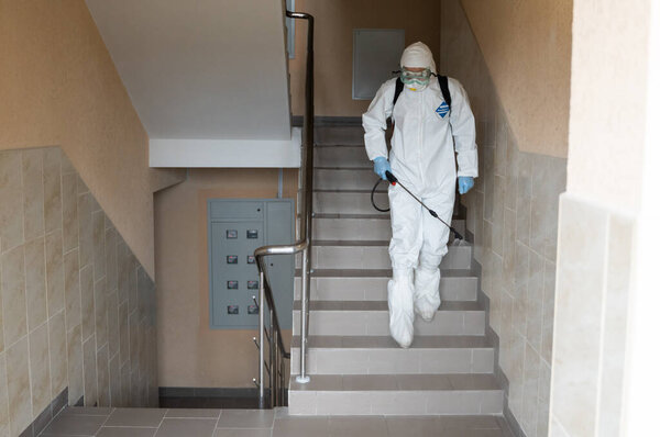 UKRAINE, KYIV - May 20, 2020: Man in a white protective suit and mask is disanitizing interior surfaces inside buildings while the coronavirus epidemic for infection prevention and control of epidemic
.