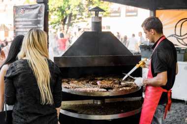 UKRAINE, LUTSK - 5 Haziran 2019: Adam yemek festivalinde domuz pirzolası pişiriyor.