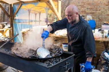 UKRAINE, LUTSK - 5 Haziran 2019: İnsanlar yemek festivalinde kabuklarda taze midyeler pişiriyor..