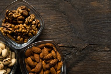 Badem, şam fıstığı ve ceviz, eski ahşap bir masanın üzerinde duran küçük bir tabakta. Fındık sağlıklı bir vejetaryen proteini ve besleyici yemektir..