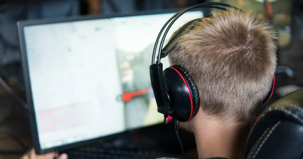 경찰, 2020 년 6 월 10 일: 컴퓨터 클럽에서 헤드폰을 끼고 비디오 게임을 하는 젊은 게이머의 뒷모습. — 스톡 사진