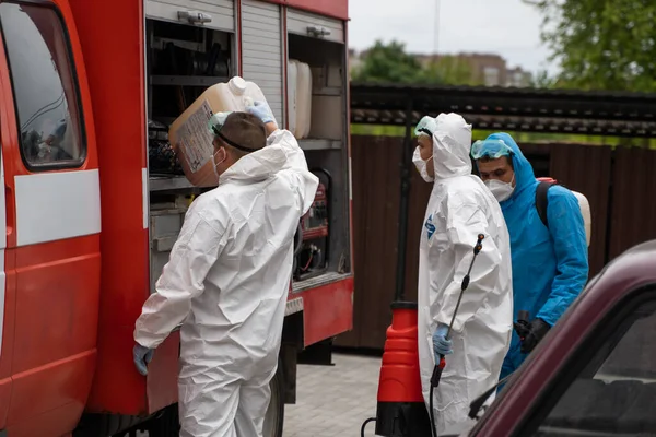 UKRAINE, KYIV - 20 mai 2020 : Un homme en costume et masque de protection blanc se tient près d'une voiture et se prépare à assainir les surfaces intérieures des bâtiments pendant l'épidémie de coronavirus. — Photo