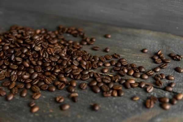 Grãos de café arábica torrados espalhados em uma mesa de madeira. Grãos de café frescos. — Fotografia de Stock