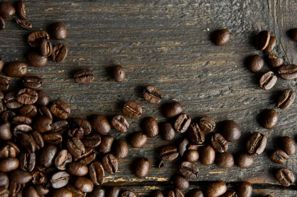 Grãos de café arábica torrados espalhados em uma mesa de madeira. Grãos de café frescos. — Fotografia de Stock