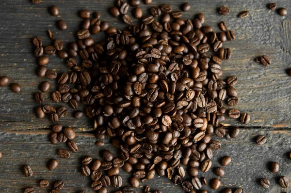 Grãos de café arábica torrados espalhados em uma mesa de madeira. Grãos de café frescos. — Fotografia de Stock