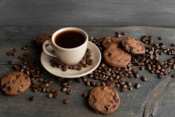 나무로 된 탁자 위에 쿠키가 놓인 커피 잔. 나무 탁자 위에 흩어져 있는 커피 원두와 쿠키가 섞인 검은 커피 덩어리. 신선 한 커피 콩. — 스톡 사진