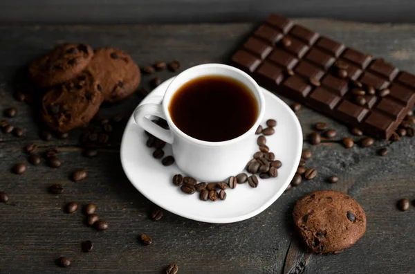 커피 컵에 쿠키와 초콜릿을 나무로 된 탁자 위에 올려 놓는다. 초콜릿 쿠키와 블랙 커피 한 조각. 신선 한 커피 콩. — 스톡 사진