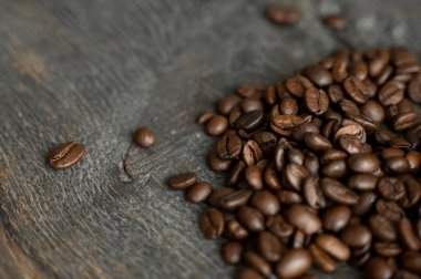 Ahşap bir masaya saçılmış kavrulmuş Arap kahve çekirdekleri. Taze kahve çekirdekleri.