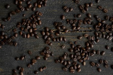 Ahşap bir masaya saçılmış kavrulmuş Arap kahve çekirdekleri. Taze kahve çekirdekleri.