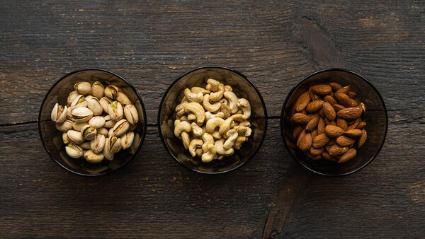 Almond, pistachio and cashew in a small plates which standing on a black table. Nuts is a healthy vegetarian protein and nutritious food.