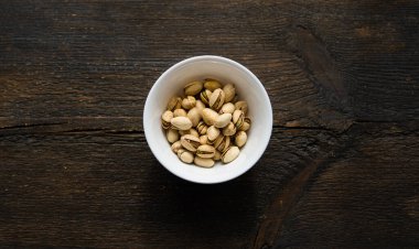 Eski ahşap bir masada küçük bir tabakta şam fıstığı. Pistachio sağlıklı bir vejetaryen protein yiyeceğidir. Doğal çerezler.