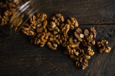 Ceviz, bir kavanozun içindeki ahşap şarap masasına saçılmış. Ceviz sağlıklı bir vejetaryen protein besleyici gıdadır. Ceviz çekirdekleri ve eski ahşap cevizler..