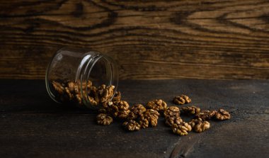 Ceviz, bir kavanozun içindeki ahşap şarap masasına saçılmış. Ceviz sağlıklı bir vejetaryen protein besleyici gıdadır. Ceviz çekirdekleri ve eski ahşap cevizler..
