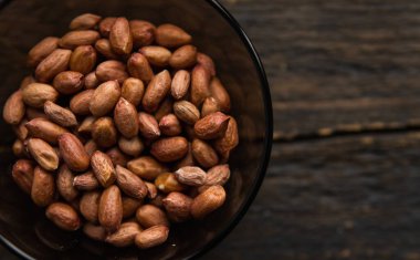 Eski ahşap bir masada küçük bir tabakta yer fıstığı. Fıstık ezmesi sağlıklı bir vejetaryen proteindir..
