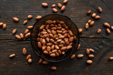 Eski ahşap bir masada küçük bir tabakta yer fıstığı. Fıstık ezmesi sağlıklı bir vejetaryen proteindir..