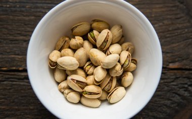 Eski ahşap bir masada küçük bir tabakta şam fıstığı. Pistachio sağlıklı bir vejetaryen protein yiyeceğidir. Doğal çerezler.