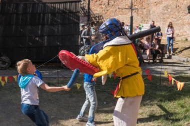UKRAINE, LUTSK - 15 Mayıs 2019: Ortaçağ şövalyesi kostümlü adam çocuklara yemek festivalinde kılıçla dövüşmeyi öğretiyor.