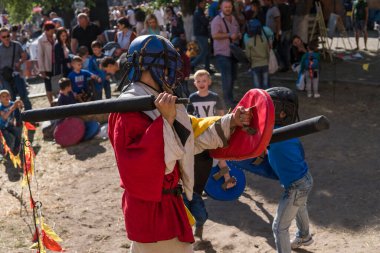 UKRAINE, LUTSK - 15 Mayıs 2019: Ortaçağ şövalyesi kostümlü adam çocuklara yemek festivalinde kılıçla dövüşmeyi öğretiyor.