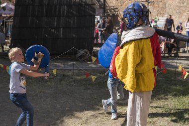 UKRAINE, LUTSK - 15 Mayıs 2019: Ortaçağ şövalyesi kostümlü adam çocuklara yemek festivalinde kılıçla dövüşmeyi öğretiyor.