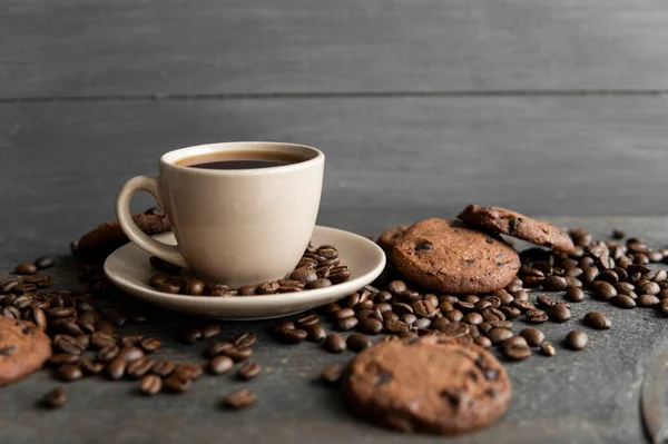 나무로 된 탁자 위에 쿠키가 놓인 커피 잔. 나무 탁자 위에 흩어져 있는 커피 원두와 쿠키가 섞인 검은 커피 덩어리. 신선 한 커피 콩. — 스톡 사진