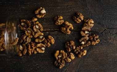 Ceviz, bir kavanozun içindeki ahşap şarap masasına saçılmış. Ceviz sağlıklı bir vejetaryen protein besleyici gıdadır. Ceviz çekirdekleri ve eski ahşap cevizler..