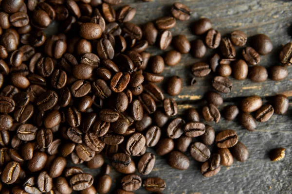 Grãos de café arábica torrados espalhados em uma mesa de madeira. Grãos de café frescos. — Fotografia de Stock