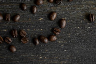 Ahşap bir masaya saçılmış kavrulmuş Arap kahve çekirdekleri. Taze kahve çekirdekleri.