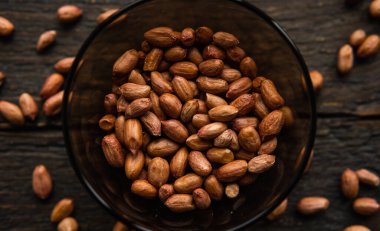 Eski ahşap bir masada küçük bir tabakta yer fıstığı. Fıstık ezmesi sağlıklı bir vejetaryen proteindir..