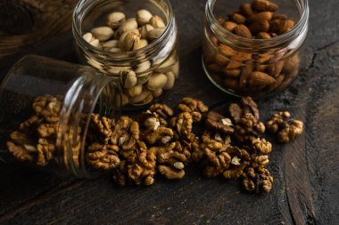 Ceviz, bir kavanozun içindeki ahşap şarap masasına saçılmış. Ceviz sağlıklı bir vejetaryen protein besleyici gıdadır. Ceviz çekirdekleri ve eski ahşap cevizler..